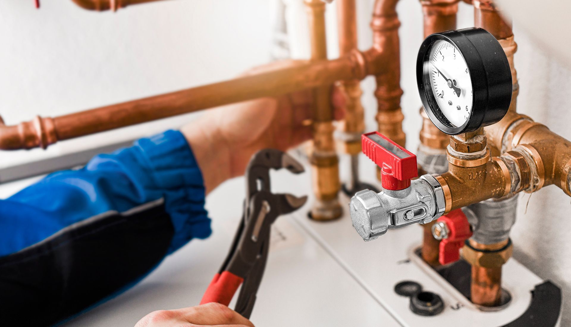 Plumber working on copper pipes with a wrench and pressure gauge, likely repairing a water system.