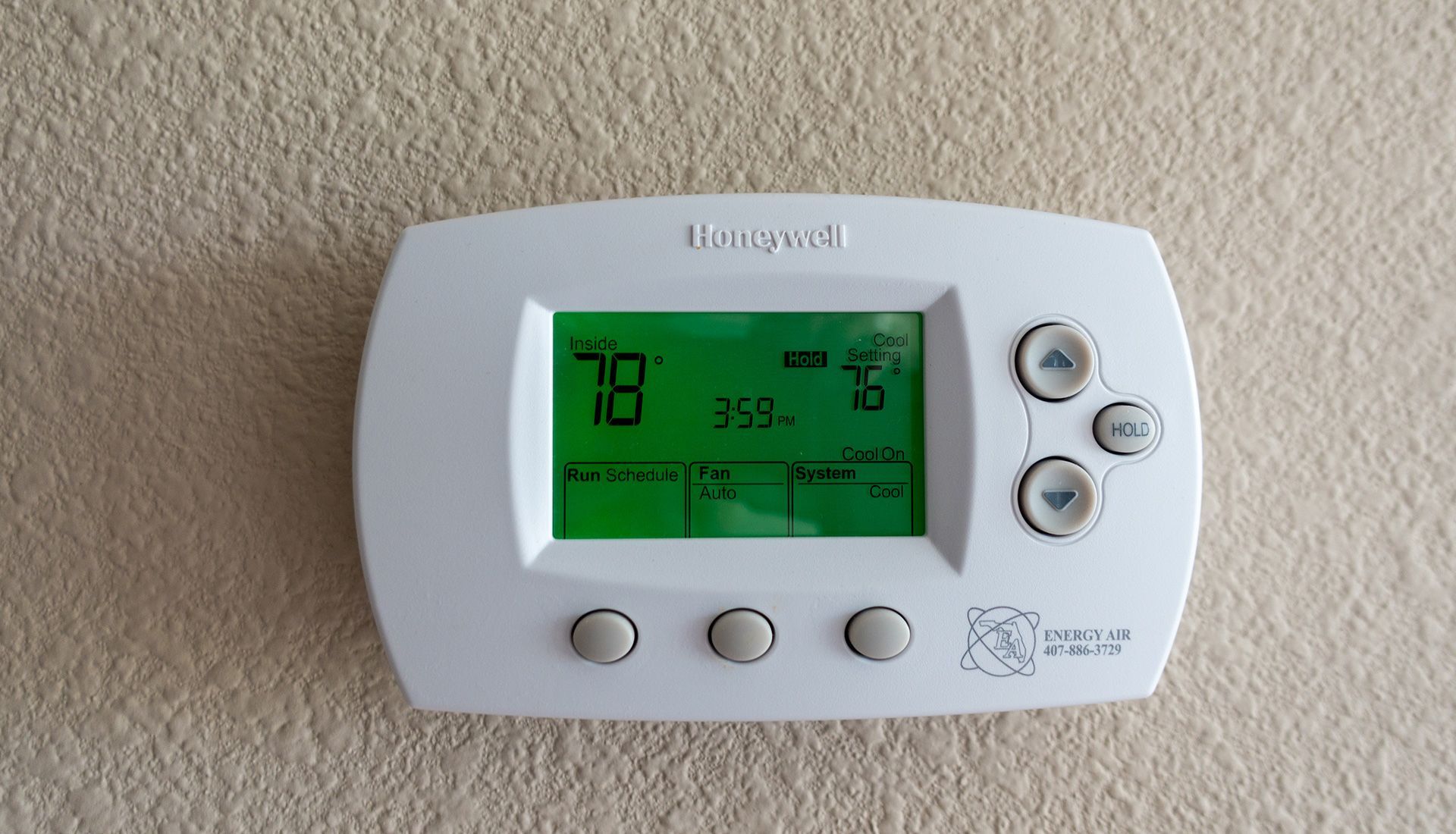 Honeywell thermostat displaying 78 degrees. It has arrows to adjust settings, mounted on a beige wall.