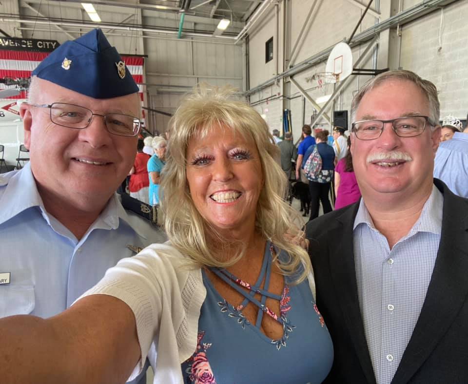 Two men and a woman are posing for a selfie in a building.