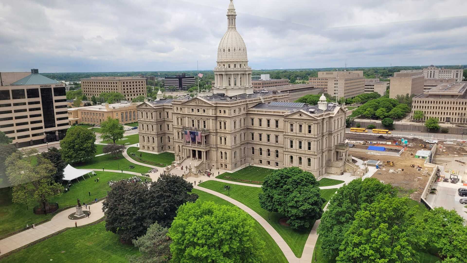 An aerial view of a large building with a dome in the middle of a city surrounded by trees.