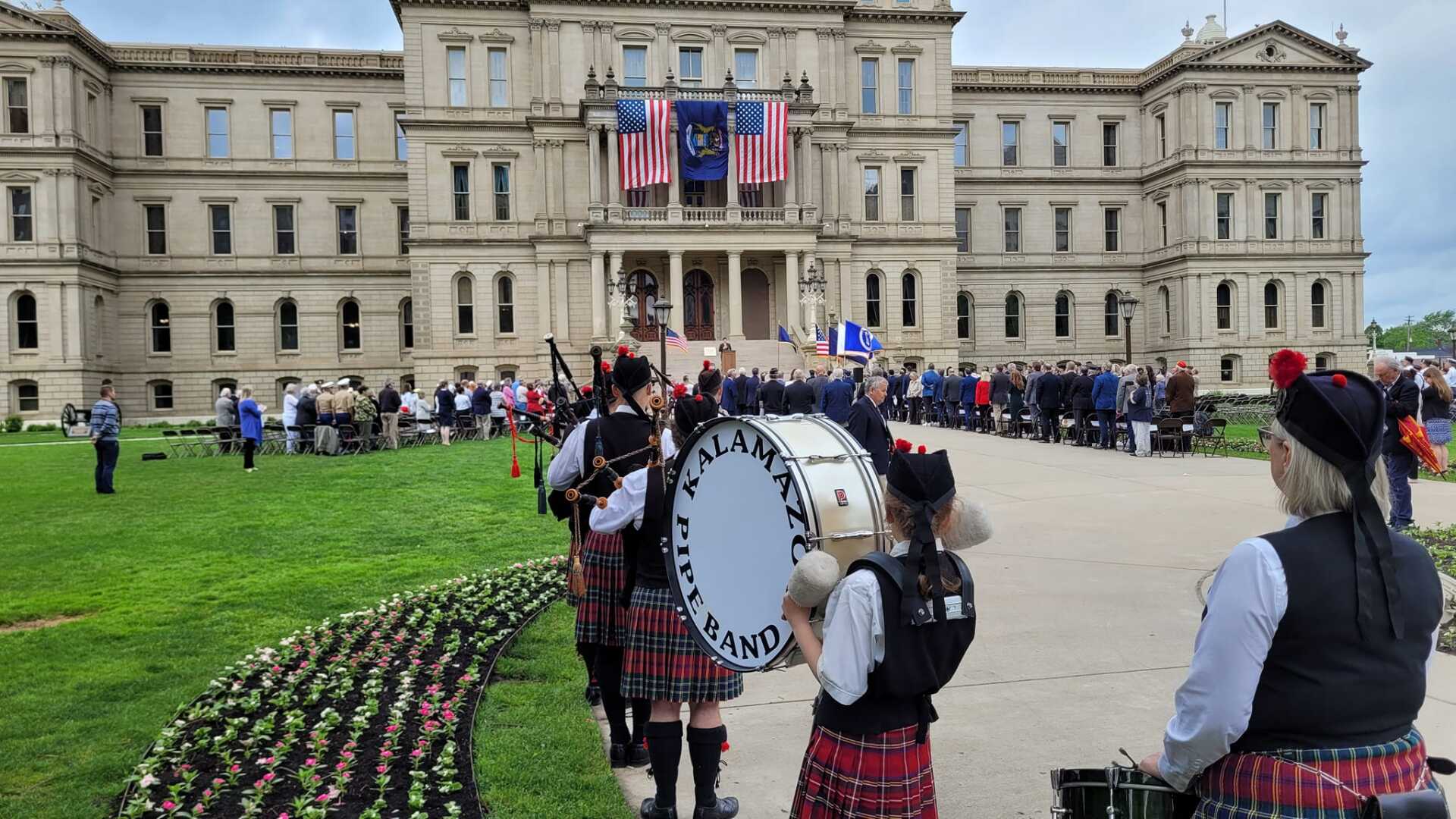 A group of bagpipe players are playing in front of a large building.