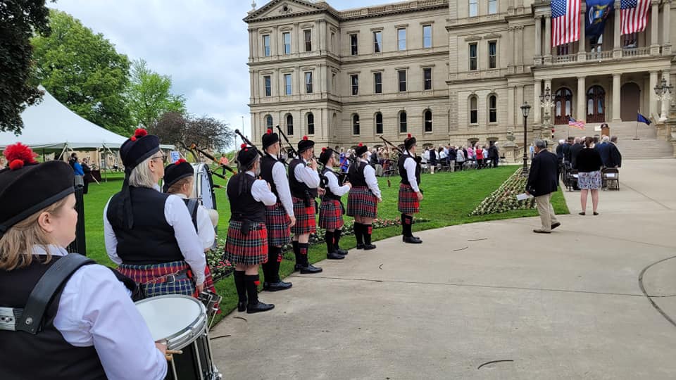 A group of bagpipe players are standing in front of a large building.