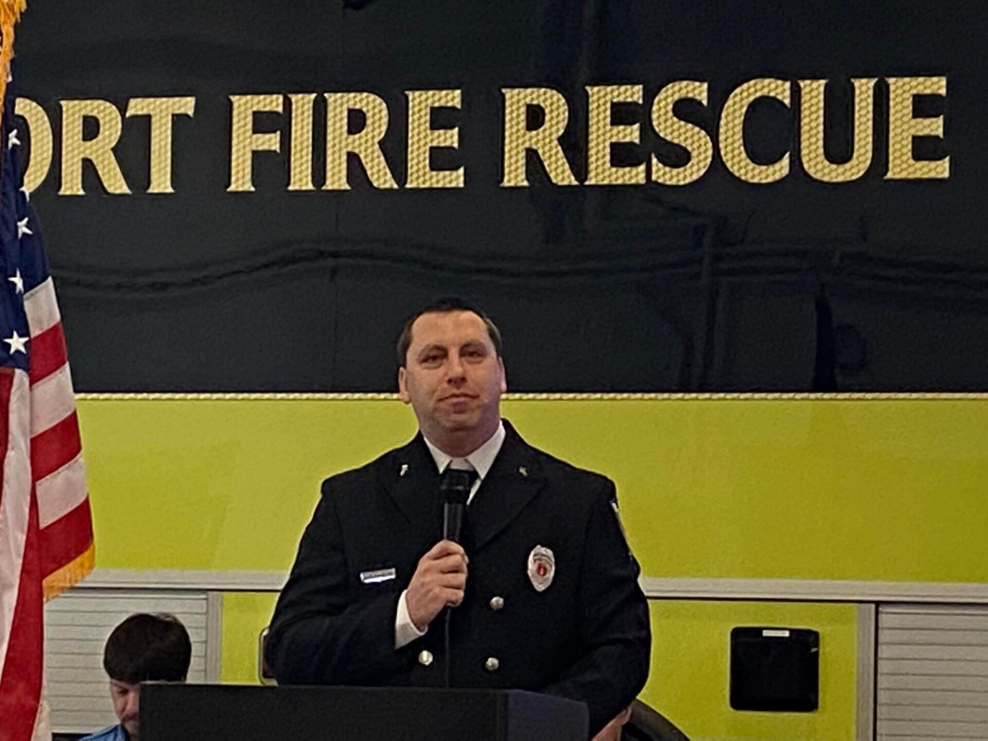 A man stands at a podium in front of a sign that says fort fire rescue