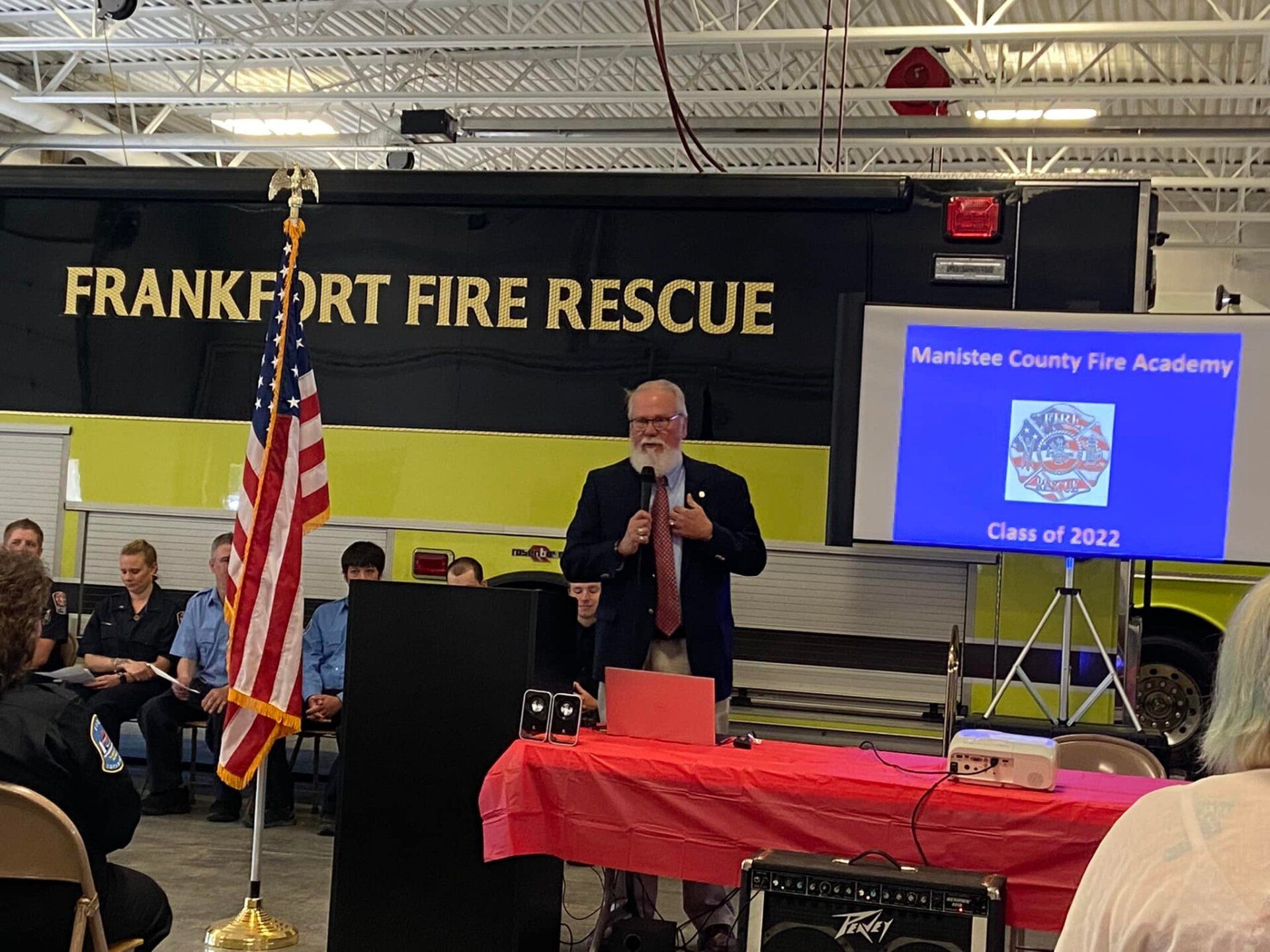 A man is giving a presentation in front of a sign that says frankfort fire rescue