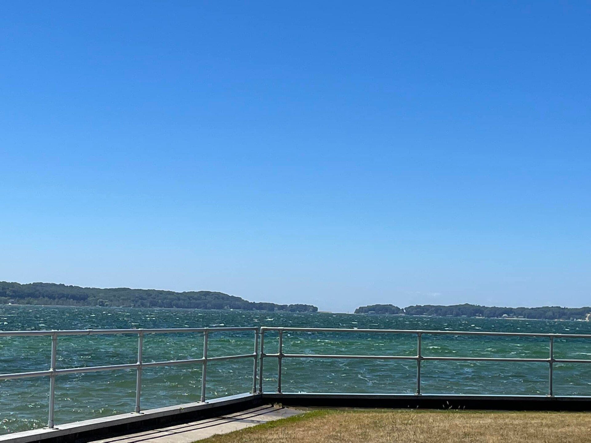 A fence surrounds a body of water with a blue sky in the background.