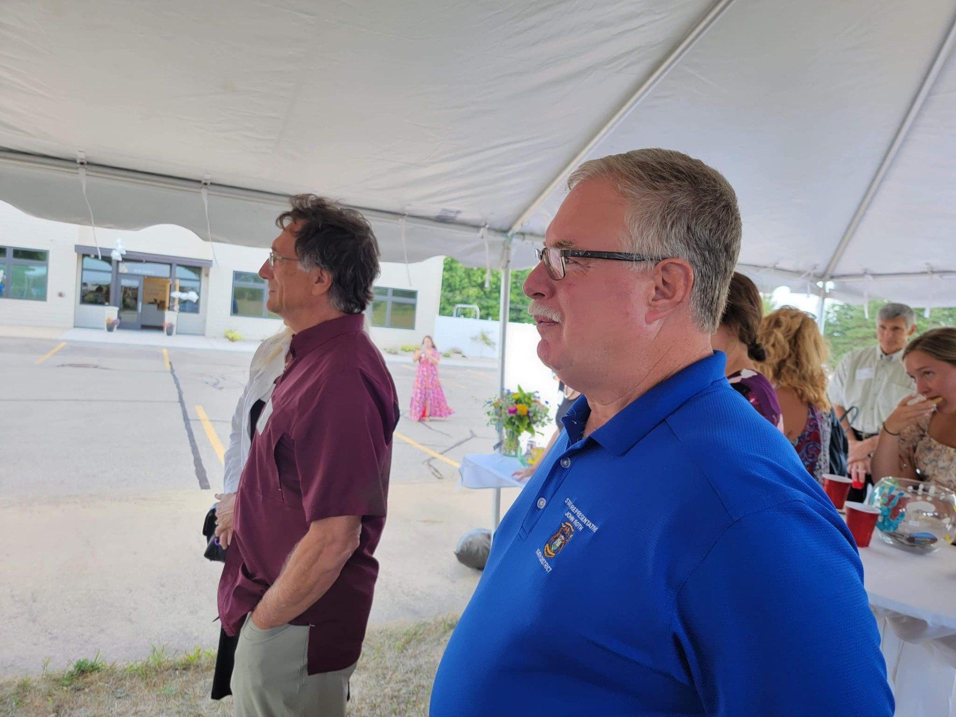 John Roth is standing in front of a group of people under a tent.