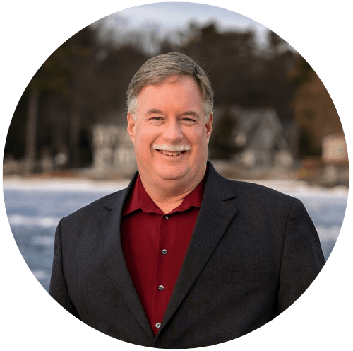 A man in a suit and red shirt is smiling in a circle