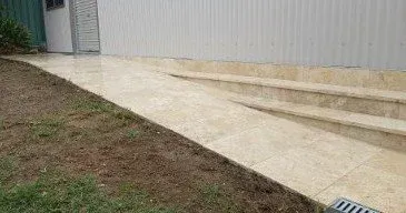 Concrete ramp and stairs leading to a building's entrance. Green grass and ground alongside.