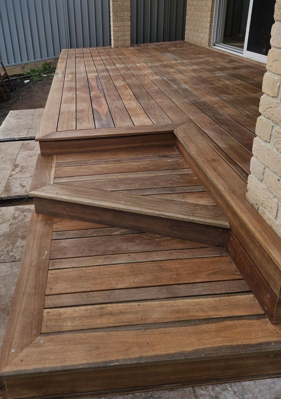 Wooden deck with steps leading down to a lower level. Natural wood tones.