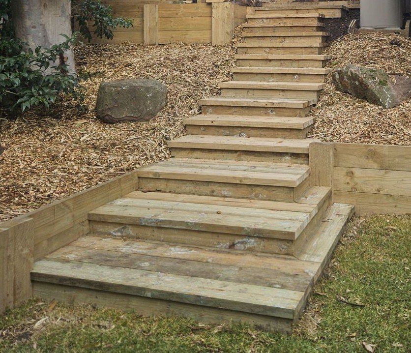 Wooden staircase built into a sloped, mulch-covered garden.