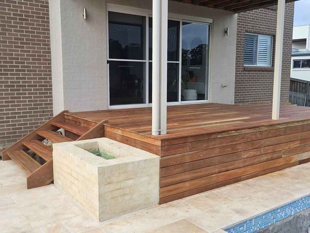 Wooden deck with stairs, built-in planter, and sliding glass doors. Exterior with brick and stone.