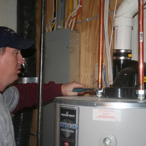 Man checking on water heater — Allegan, MI — Tim Rogers Plumbing LLC Man checking on water heater — Allegan, MI — Tim Rogers Plumbing LLC