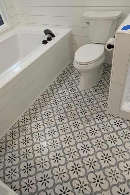 Small bathroom with patterned tile floor, white toilet, and white bathtub with shower caddy.