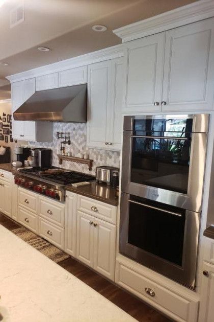Modern kitchen with white cabinets, stainless steel appliances, and a black countertop