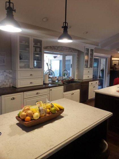 Modern kitchen with a large island, hanging lights, and a fruit bowl on the counter