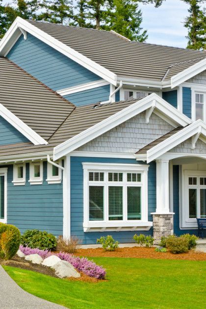 Blue suburban house with white trim, gray roof, and a landscaped front lawn