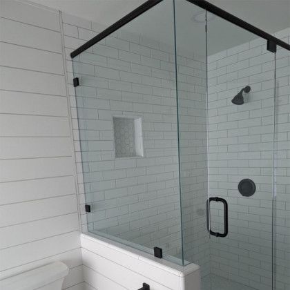 Modern white-tile bathroom with a glass-enclosed shower and black fixtures
