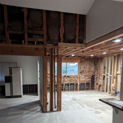 Partially demolished interior with exposed studs, insulation, and open wall framing during renovation
