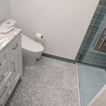 Small bathroom with toilet, vanity, gray tile floor, and glass shower enclosure