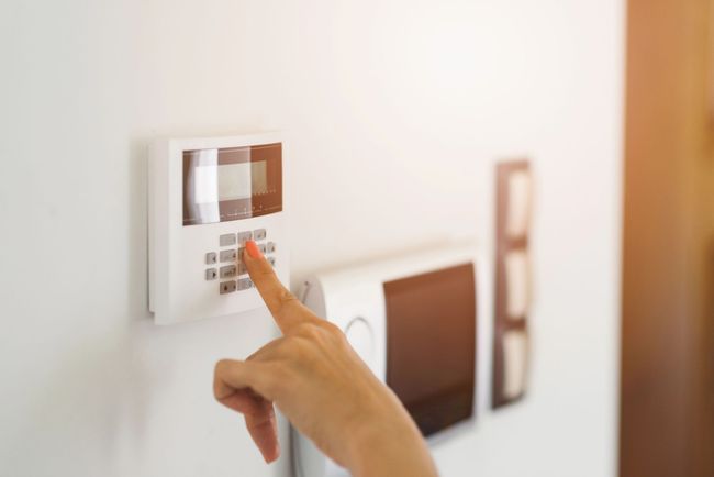 Mano che preme il pannello di controllo del termostato a parete in una stanza luminosa