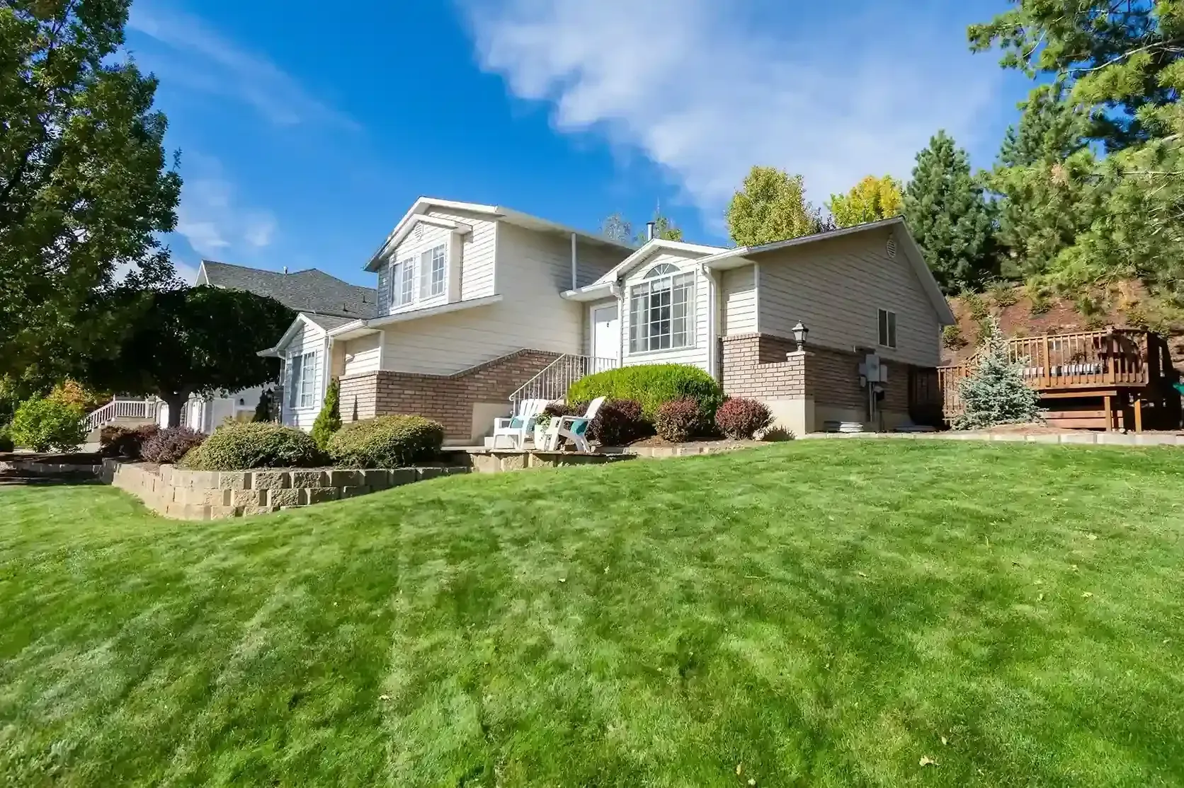 Suburban house with stone facade, manicured lawn, and bright blue sky