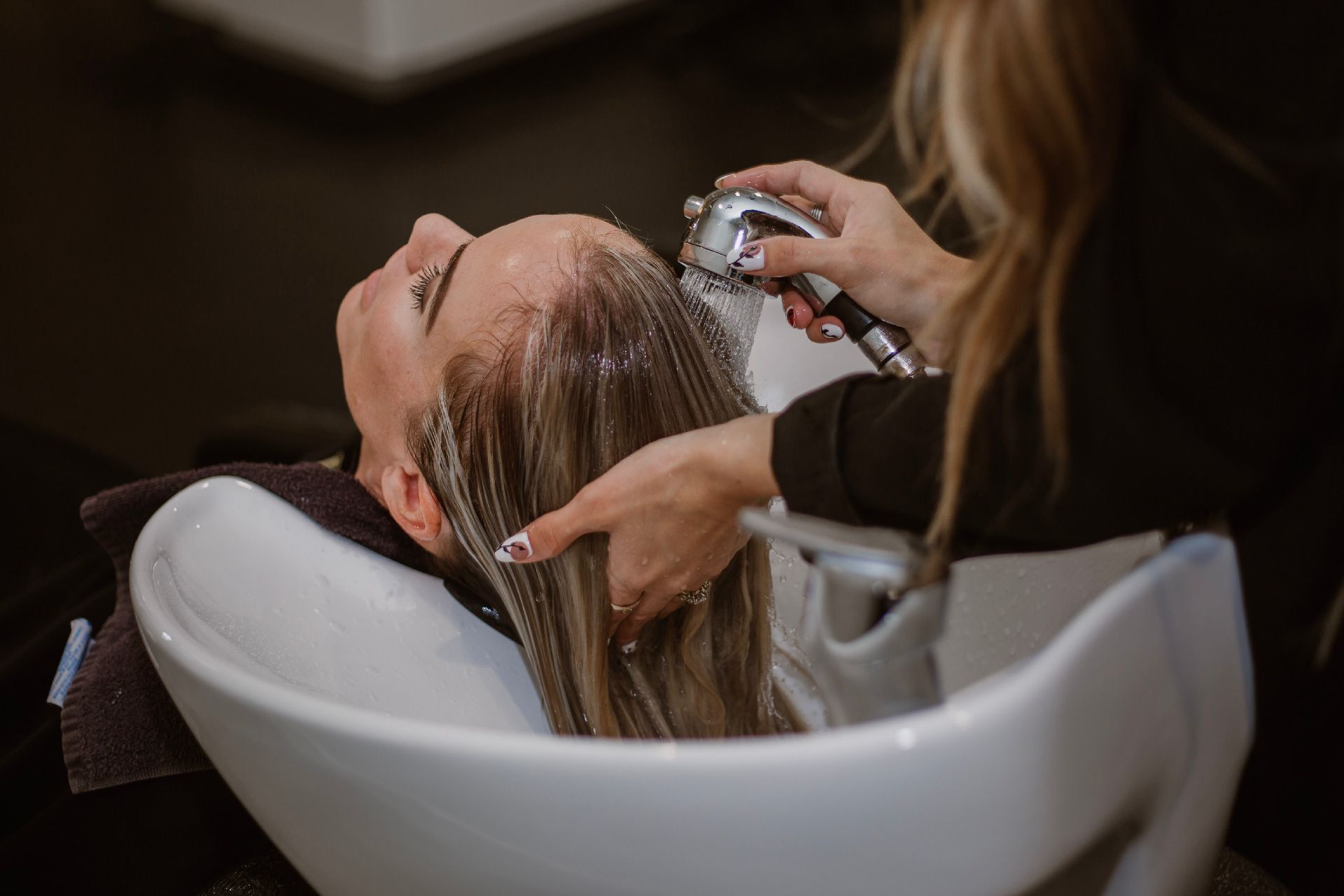 Una mujer se lava el cabello en un lavabo de una peluquería.