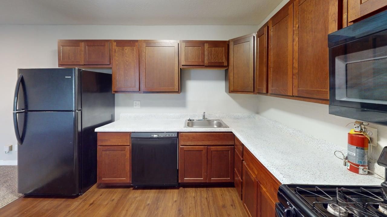 Garden Pointe kitchen with brown cabinets, a fridge, and a dishwasher