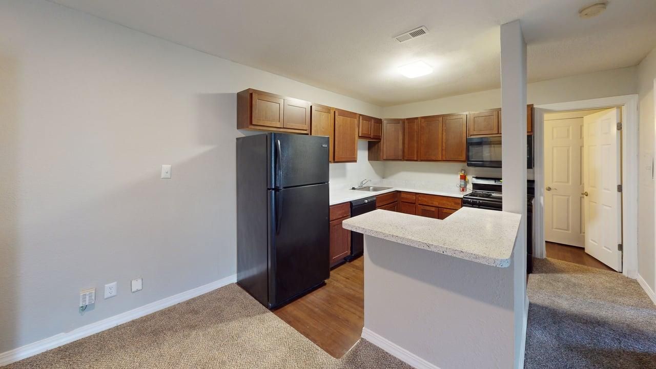 Kitchen with brown cabinets, a dishwasher, stove, and fridge.