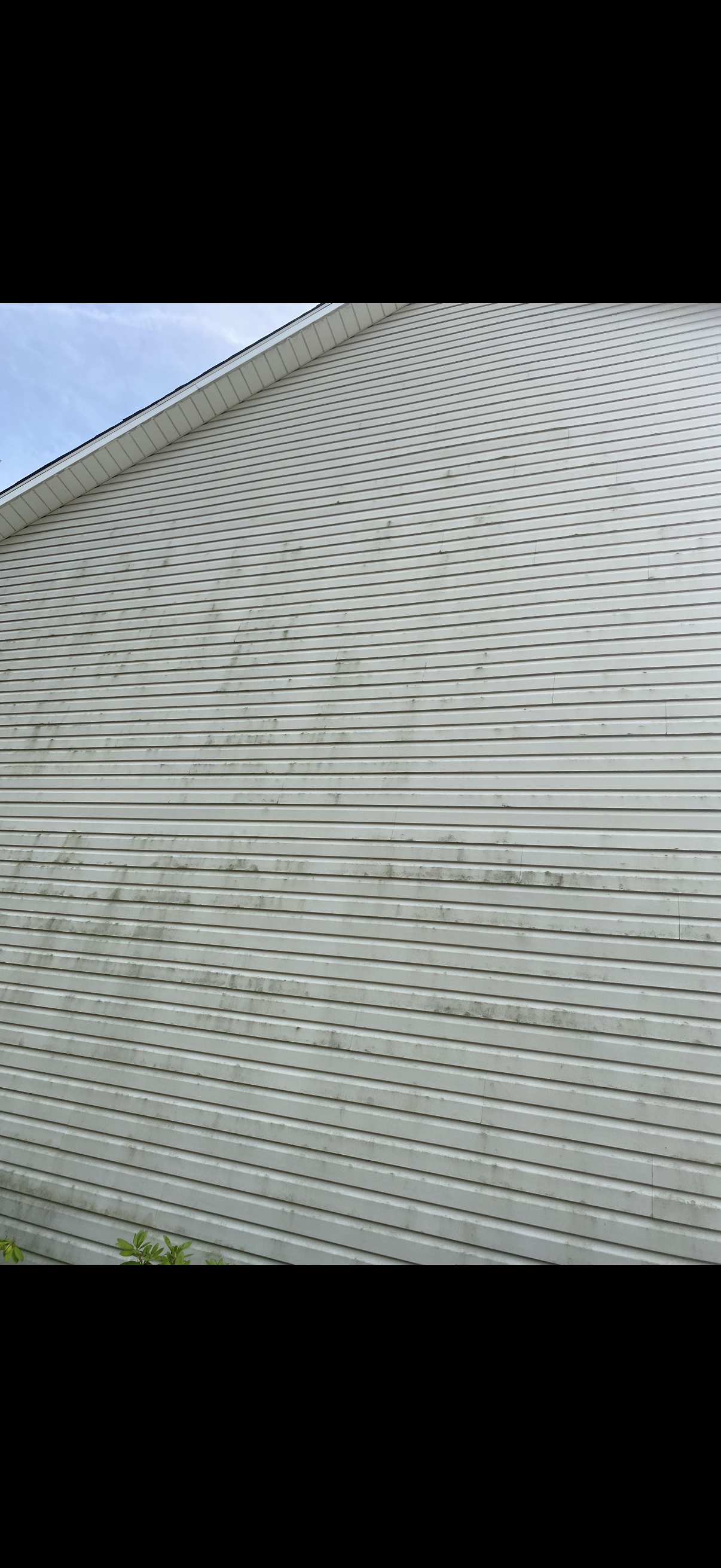 Close-up of white house siding with a decorative wave-like texture near the roofline