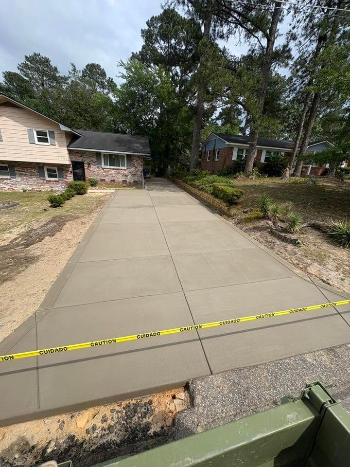 Fresh concrete driveway under construction, blocked off with caution tape in a residential neighborhood.
