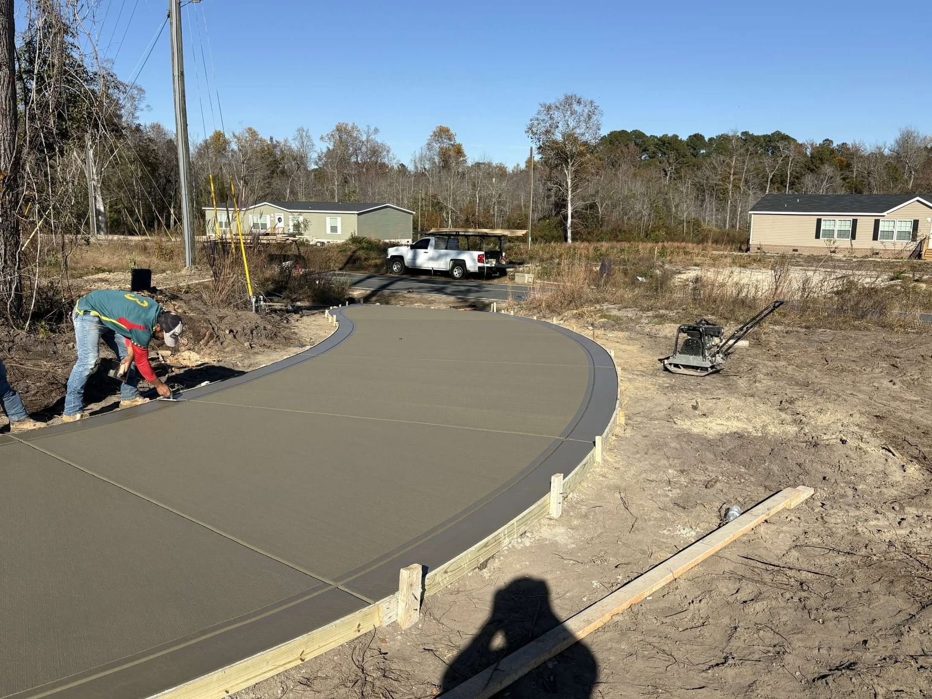 Workers pouring a curved concrete driveway in a suburban yard on a sunny day