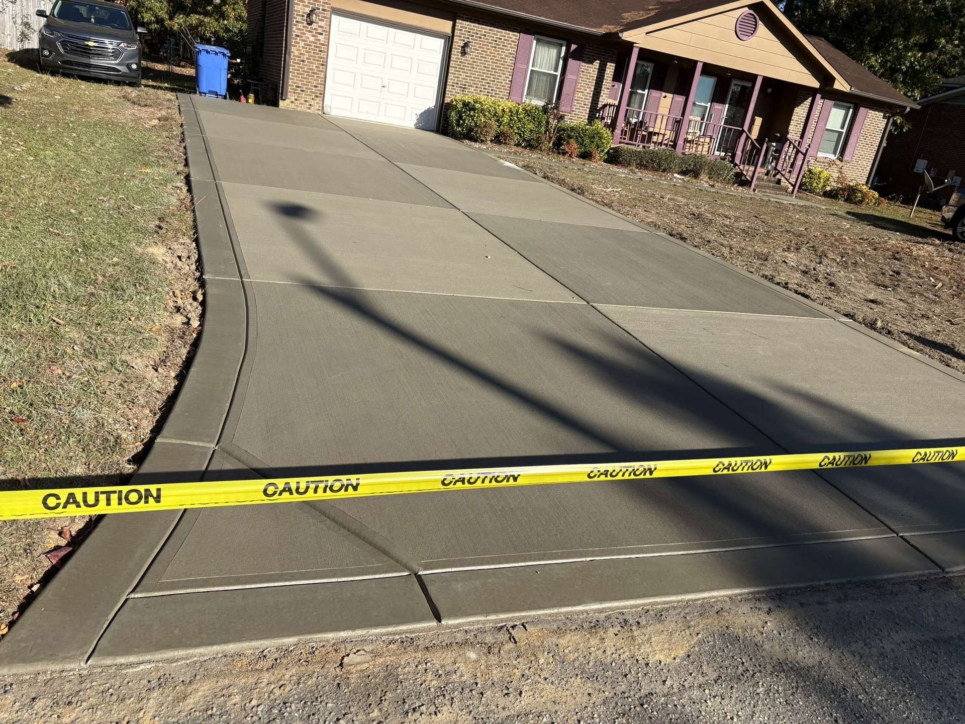Yellow caution tape blocks a driveway in front of a house and garage.