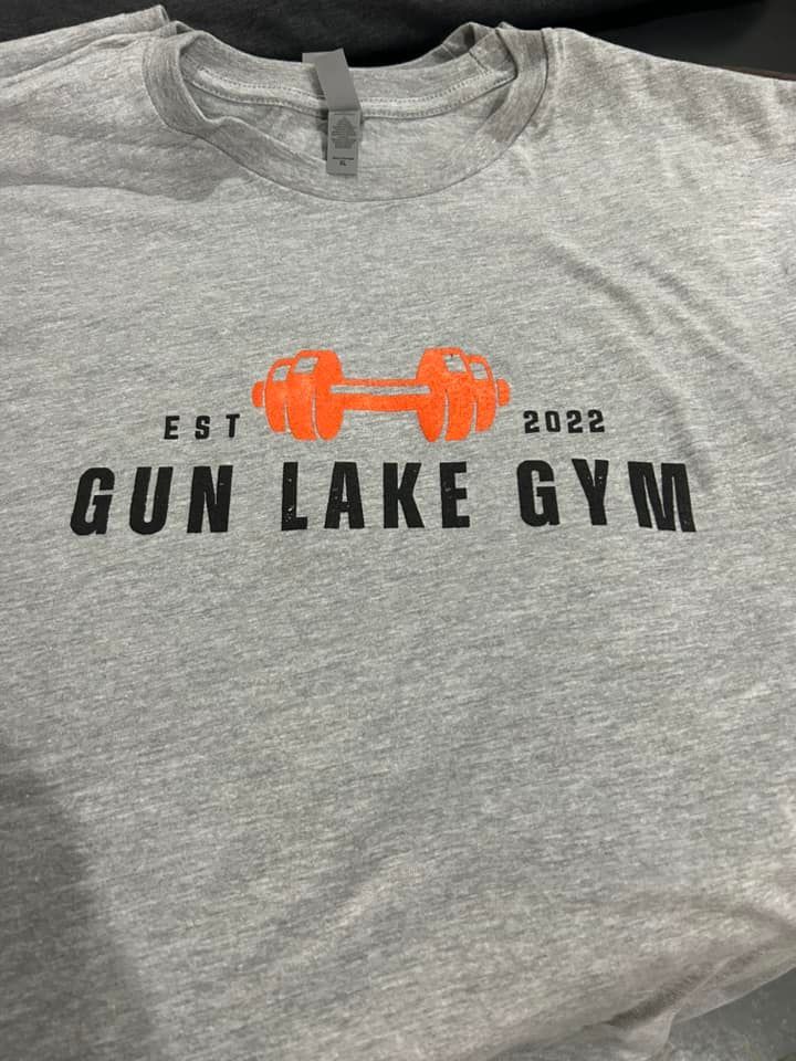 A heather gray t-shirt featuring an orange dumbbell icon above