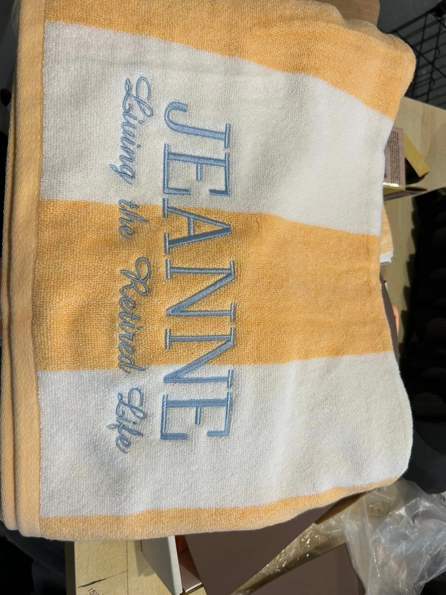 A gold and white striped towel embroidered with the name