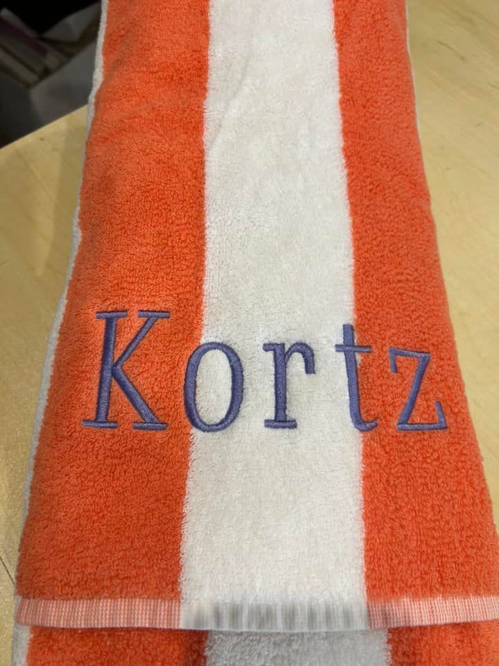 An orange and white striped towel embroidered with the name