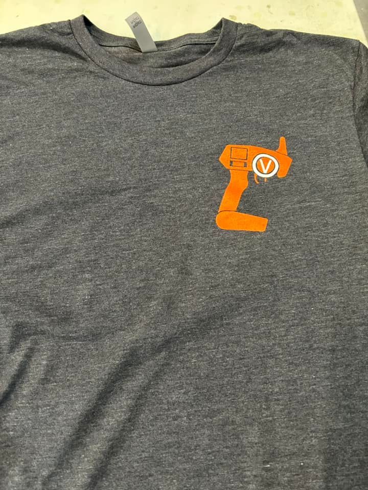A gray heather t-shirt featuring an orange graphic of an RC car remote control with a white circled