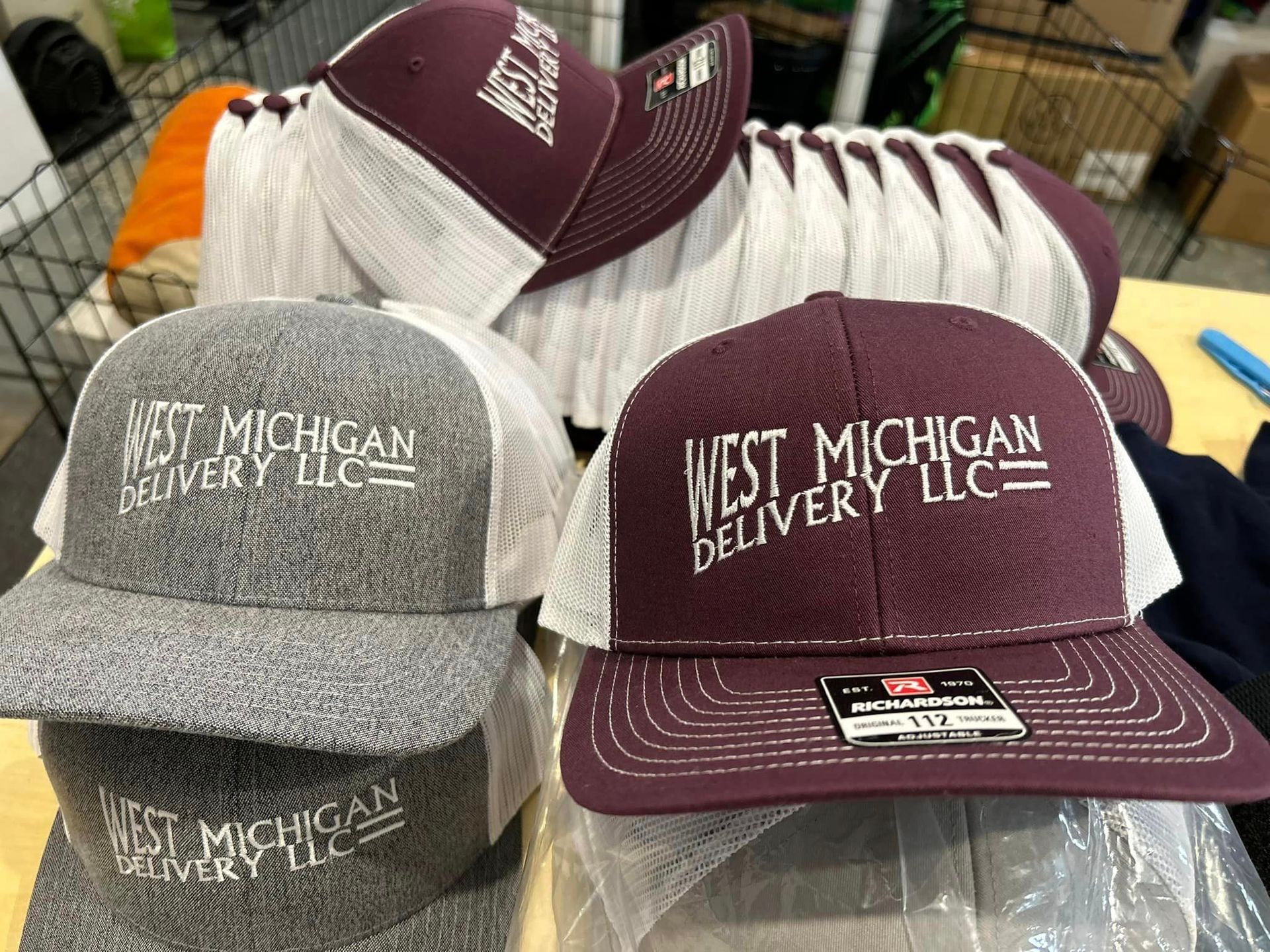 Maroon and grey trucker-style hats embroidered with the logo