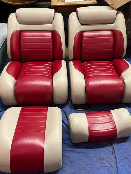 Red and cream leather car seat cushions and panels laid out on a blue tarp.