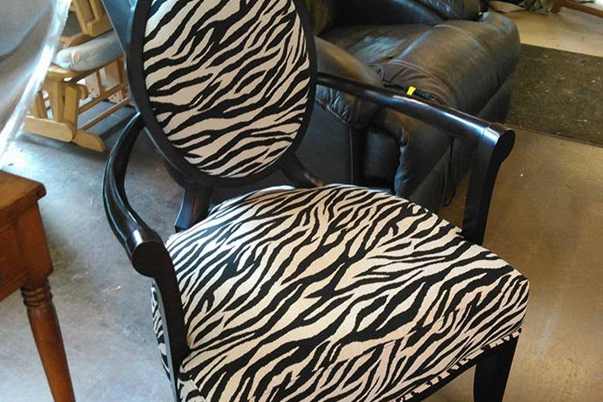 Black chair with zebra-striped cushion and backrest in a room with furniture nearby