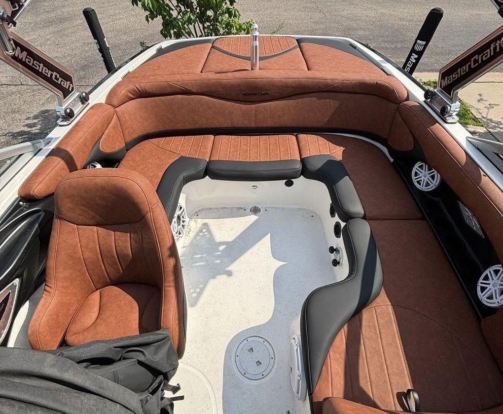 Orange-cushioned boat cockpit with white floor and steering wheel, viewed from above