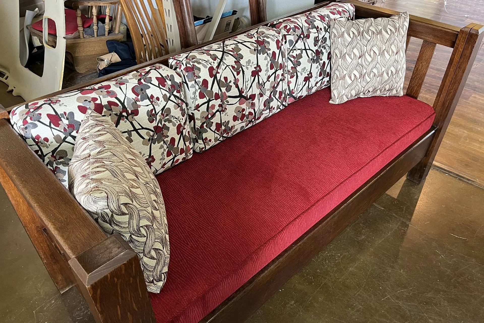 Wooden bench with red cushion and floral back and side pillows in a room