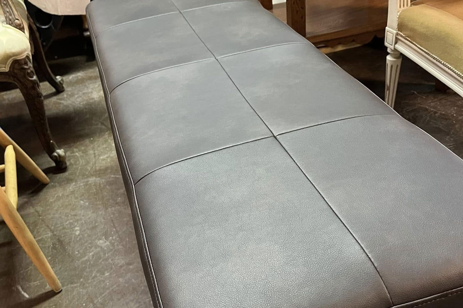 Black cushioned bench with stitched square panels in a furniture showroom