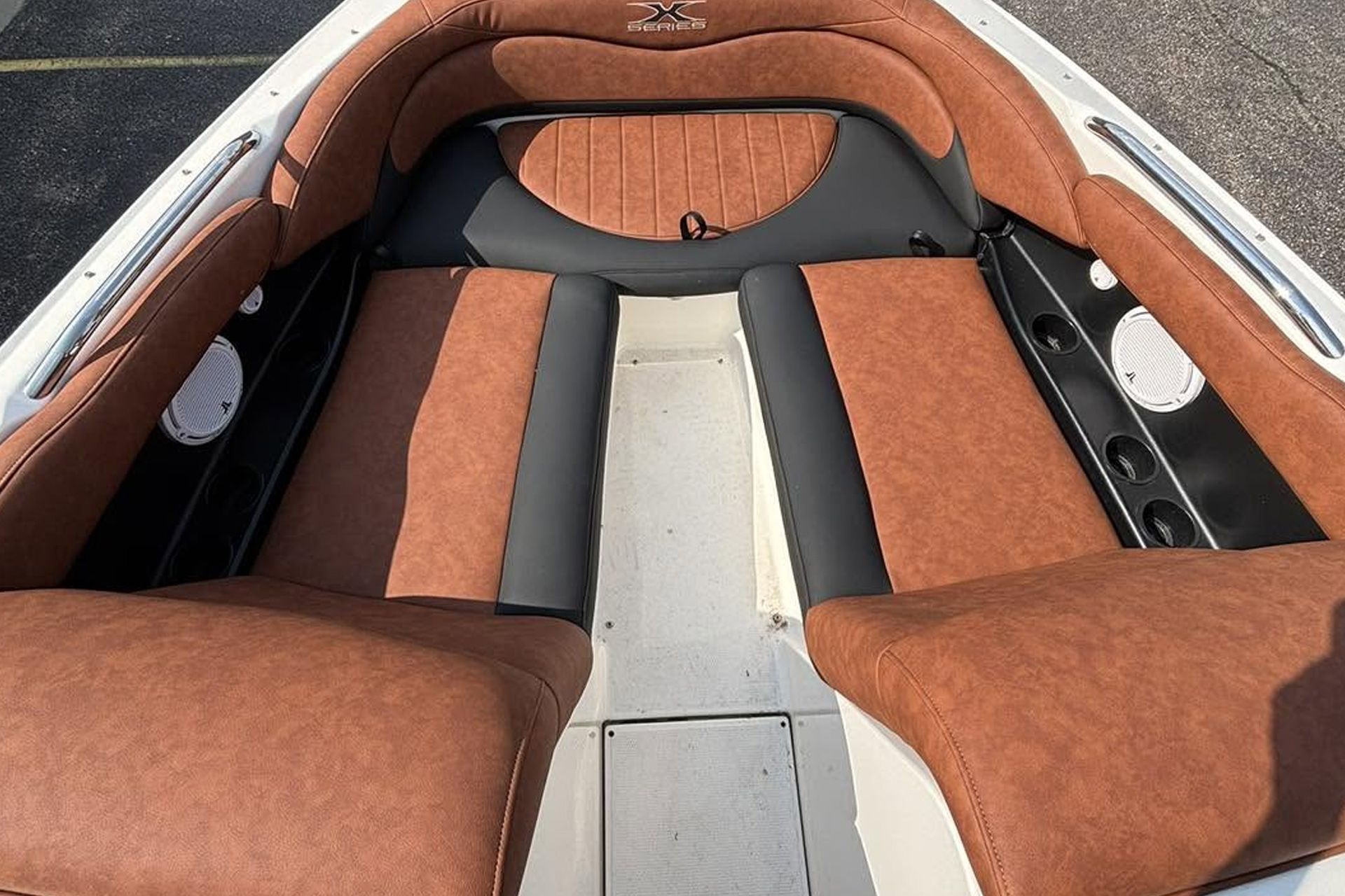 Boat cockpit with brown and gray upholstered seats and side speakers along the deck
