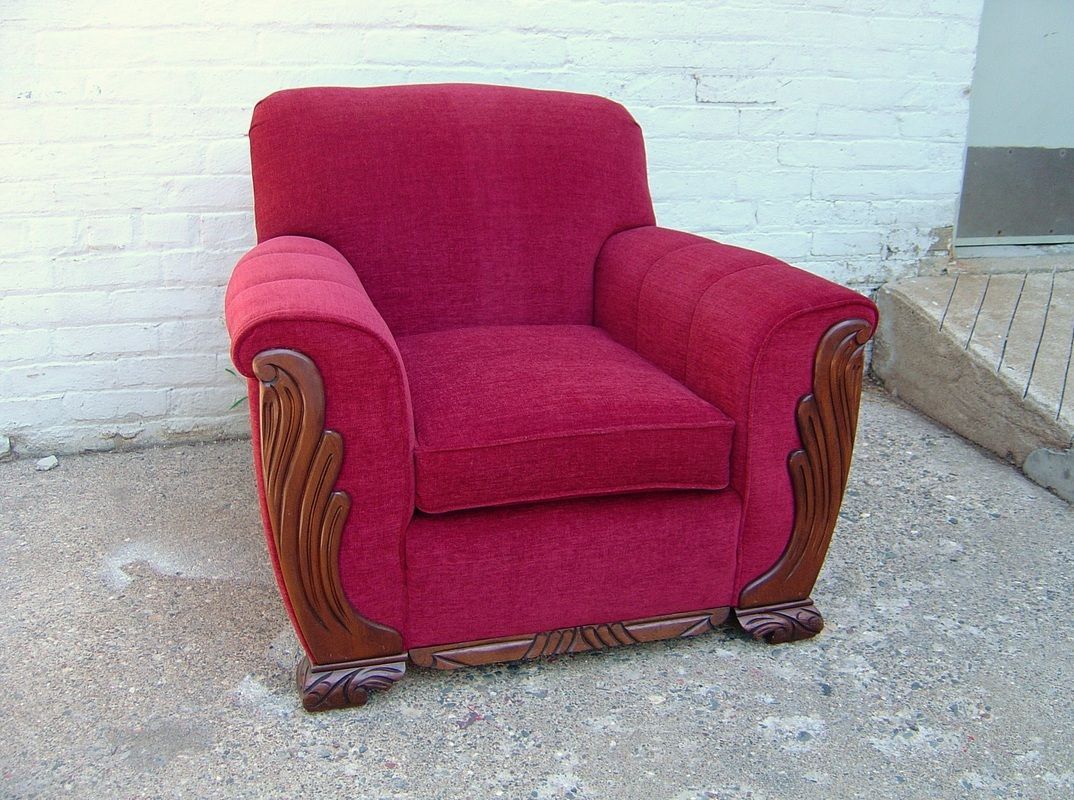 A red chair is sitting in front of a white brick wall.
