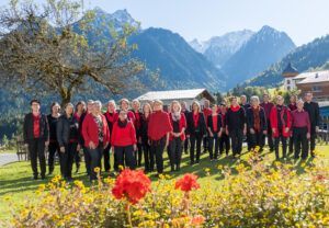 Eine große Gruppe von Menschen steht auf einem Feld mit Bergen im Hintergrund.
