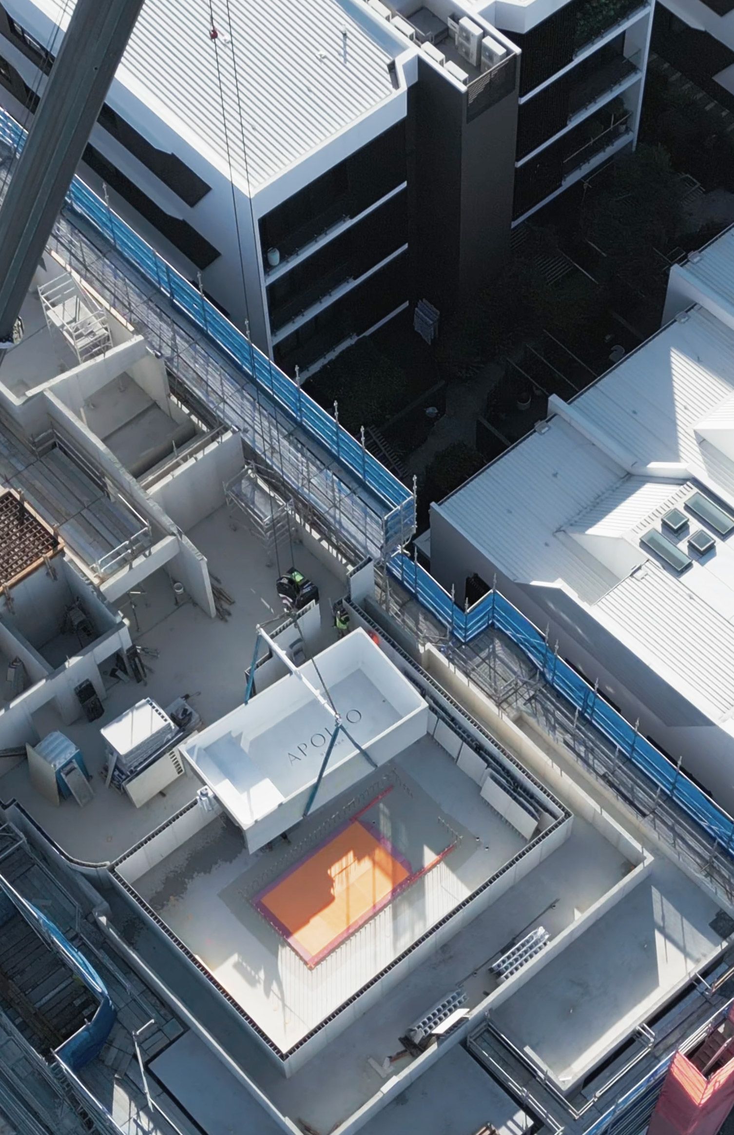 Overhead view of modern buildings with rooftops and walkways; a rectangular orange structure is visible.