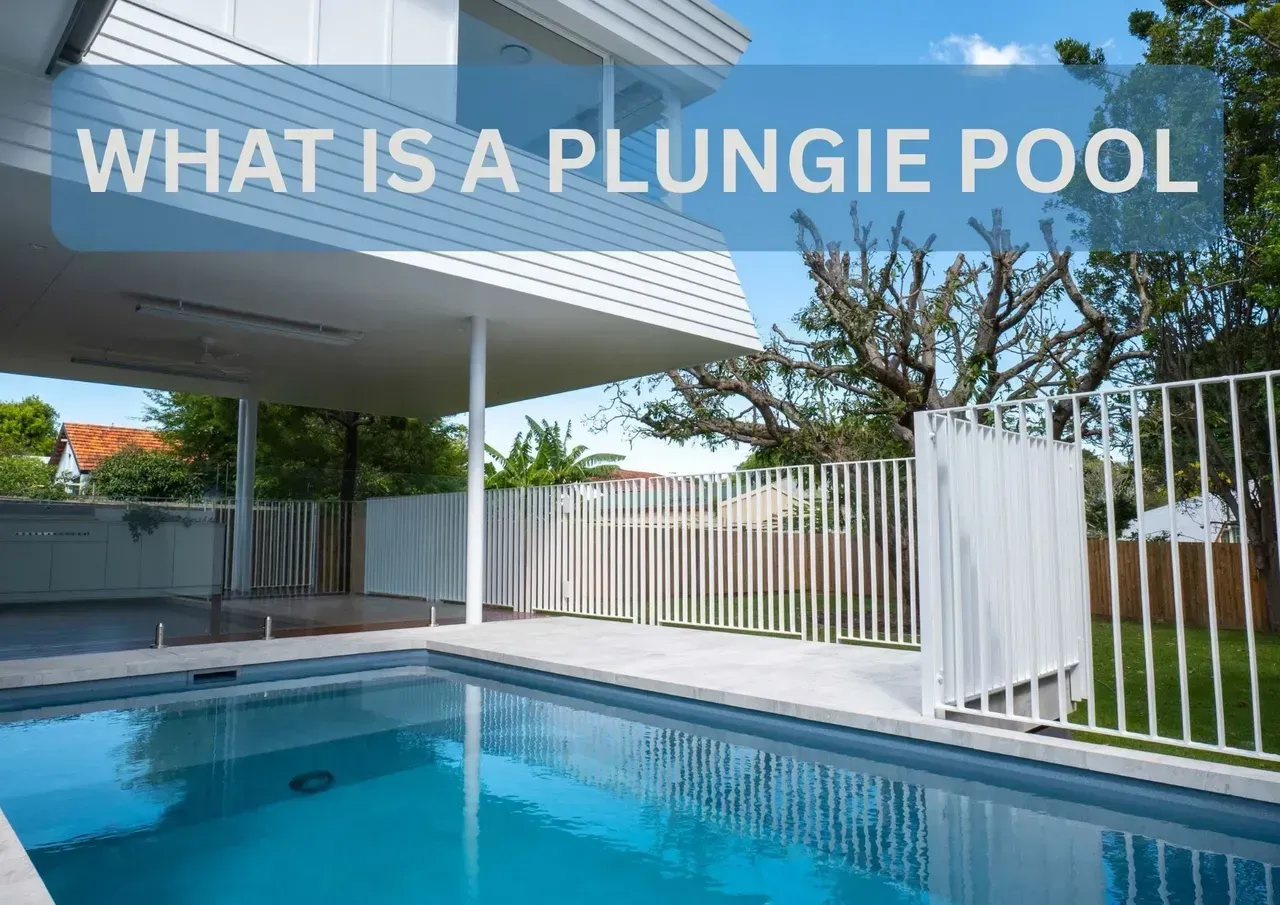 A modern home with a rectangular plunge pool. The turquoise pool is in front of a white patio with a white fence on the side.