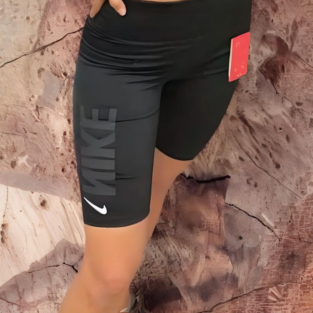 Pantalones cortos deportivos Nike negros con logotipo y etiqueta roja, usados por una persona.