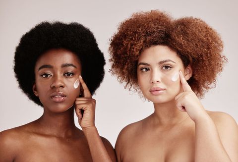 Two women are applying lotion to their faces.
