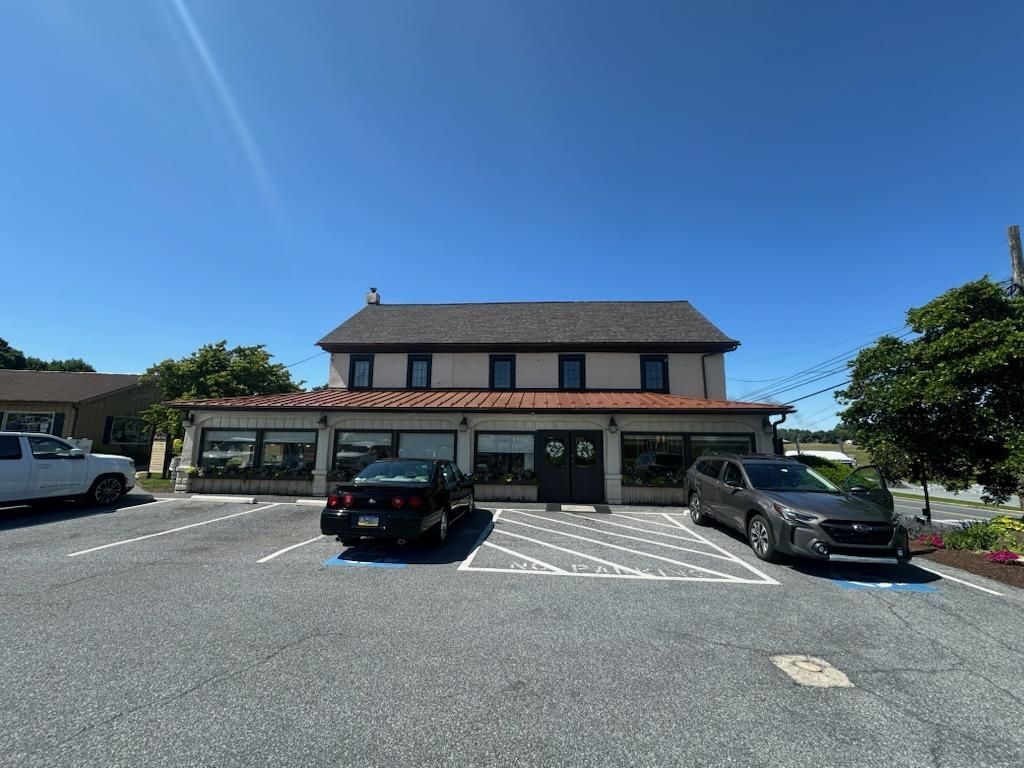 Parking lot in front of a low building with parked cars under a clear blue sky